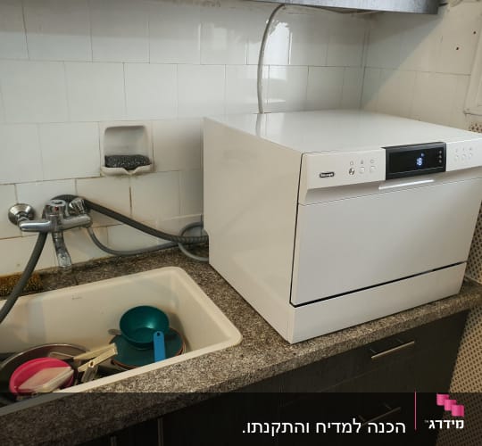 כיור עם כלים, ברז וצינור מחובר למדיח כלים